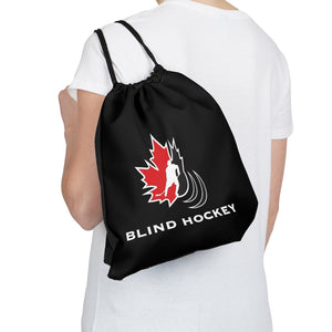 individual holding a black drawstring bag with the Canadian blind hockey logo on it over their shoulder. 